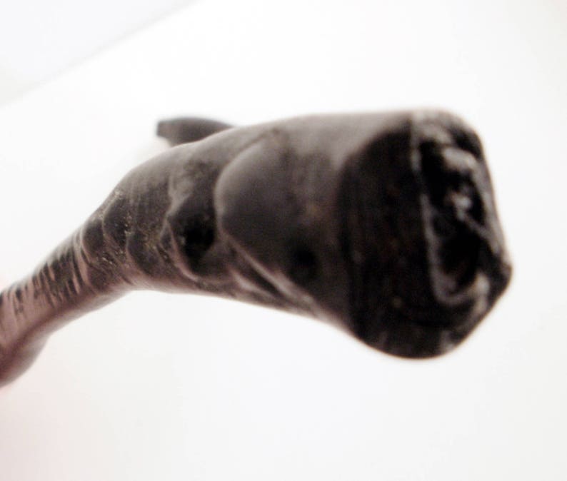May include: A close-up of a dark brown, wooden walking stick with a curved handle.