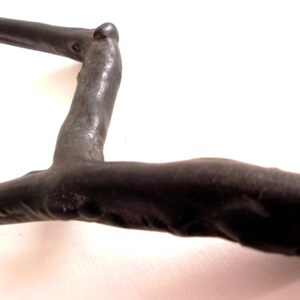 May include: A black, wooden, branch-shaped sculpture with a smooth, polished finish. The sculpture is shaped like a letter L with a curved top.