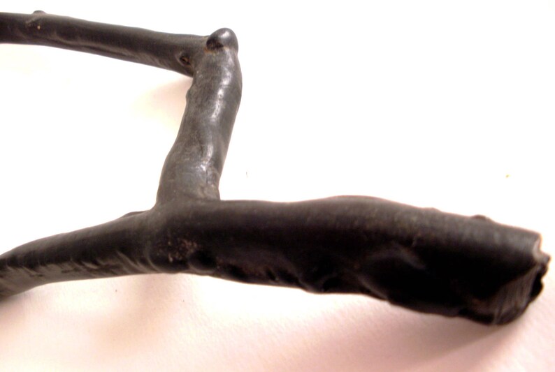May include: A black, wooden, branch-shaped sculpture with a smooth, polished finish. The sculpture is shaped like a letter L with a curved top.