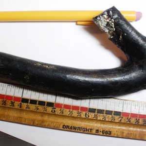 May include: A black wooden ruler with red and black markings. The ruler is labeled "DRAWRIGHT S-663". A black branch with a rough texture is placed on top of the ruler.