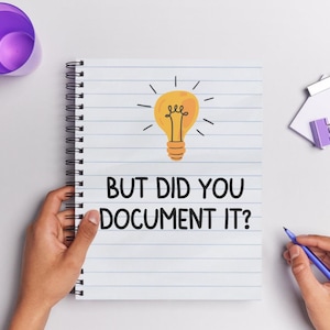 May include: A spiral-bound notebook with lined paper, featuring a drawing of a lightbulb and the text "BUT DID YOU DOCUMENT IT?". A purple pen and a purple cup are also visible.