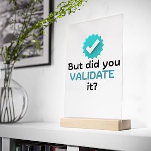 May include: A white sign with a blue tick icon and the text "But did you validate it?" on a wooden stand.