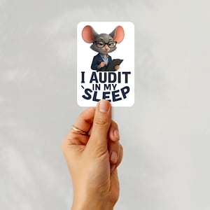May include: A rectangular sticker featuring a cartoon mouse wearing glasses and a suit, holding a clipboard. The sticker has the text "I AUDIT IN MY SLEEP" in navy blue. The sticker is held by a hand with a gold ring.