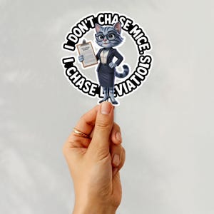 Op de afbeelding: Een sticker met een cartoonkat in een pak, met een bril en een klembord. De sticker heeft een cirkelvormig ontwerp met de tekst "I DON'T CHASE MICE. I CHASE DEVIATION."