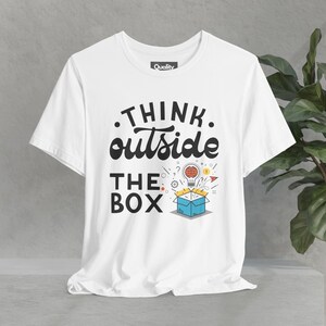 May include: White t-shirt with a black graphic that says "Think outside the box". The graphic features a light bulb with a brain inside, popping out of a box.