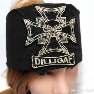 May include: Black cap with an embroidered design featuring a skull within a cross and the text "DILLIGAF" in a rectangular patch. The embroidery is in a contrasting light color.