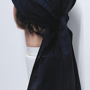 May include: A dark navy blue head covering, possibly a bandana or head wrap, with a tied back. The fabric appears to be a soft, solid material. The head covering is shown on a mannequin head.