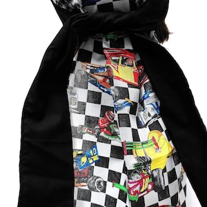 May include: A black and white checkered head covering with a racing car print. The head covering has a black scarf-like extension. The racing car print features various colorful race cars.