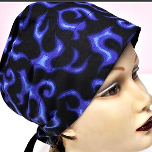 May include: A black cap with a blue flame pattern. The cap is tied in the back with black ties. The cap is made of fabric and is worn on the head.