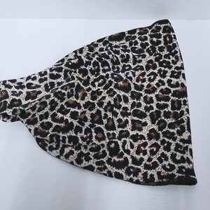 May include: A leopard print headband in shades of brown, black, and cream. The fabric is soft and flexible, designed to fit comfortably around the head. The headband is a stylish accessory.