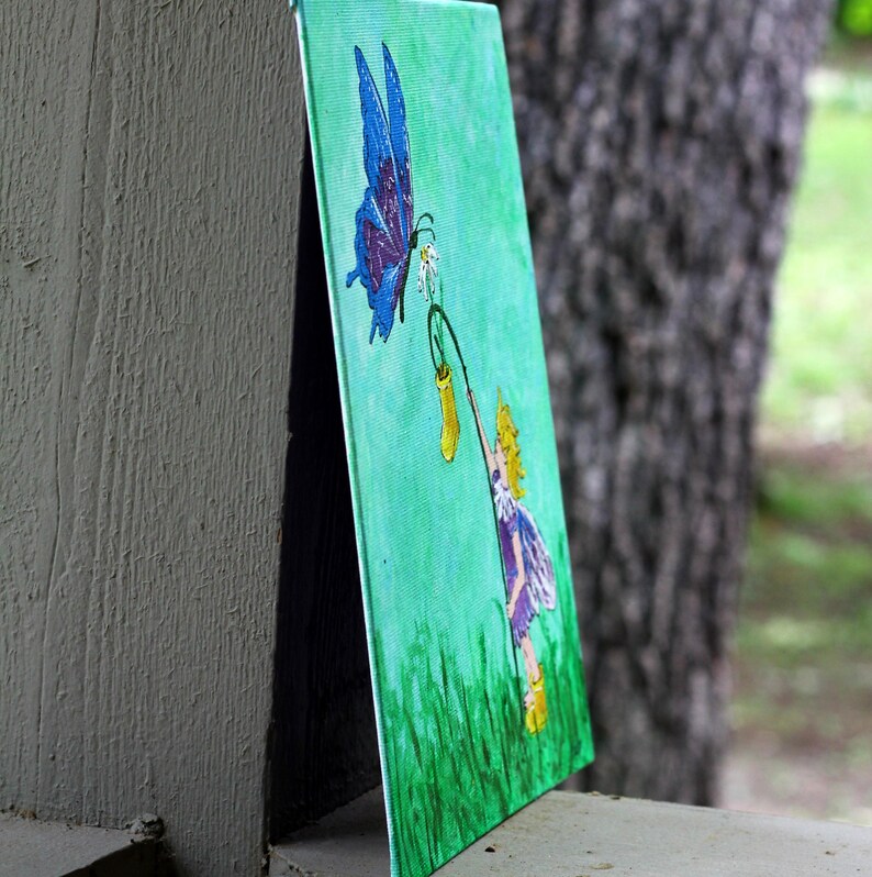 May include: A canvas painting featuring a blue butterfly with purple accents hovering near a small girl in a purple dress. The girl holds a yellow lantern in a green field. The background is a light green color.