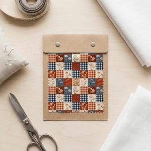 May include: A fabric swatch card featuring a patchwork design of alternating squares. The pattern includes blue and white gingham, red and white gingham, and cream squares decorated with various floral illustrations in shades of red and blue.