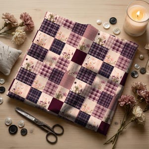 May include: A square piece of fabric featuring a patchwork design of alternating squares. Some squares display a dark purple and light pink plaid pattern, while others feature a light cream background with printed wildflowers in shades of pink and purple.