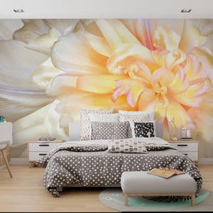 May include: A bedroom with a large floral mural in shades of yellow, peach, and white. The bed has a gray polka-dot comforter and decorative pillows. A white desk and chair are in the corner, and a small ottoman sits at the foot of the bed.