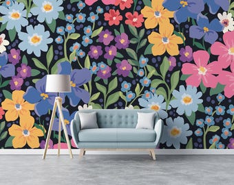 May include: A blue sofa with two pillows sits in front of a wall with a floral pattern. The pattern features a variety of flowers in shades of blue, pink, yellow, and purple on a dark background.