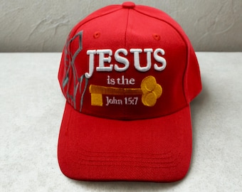 May include: Red baseball cap with the embroidered text "JESUS is the" and "John 15:7". The cap features a key design and a gray decorative element on the side.