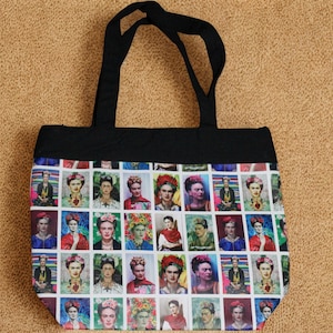 May include: A tote bag featuring a repeating pattern of Frida Kahlo portraits. The bag has a black top and handles, with a colorful array of images on the main body. The background is a neutral tan color.