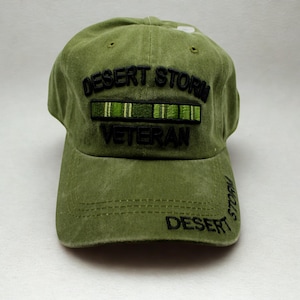 Puede incluir: Gorra de béisbol verde oliva con el texto "DESERT STORM VETERAN" bordado en negro. La gorra tiene una visera curva y una corona estructurada, adecuada para actividades al aire libre.