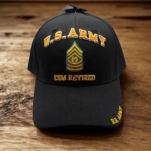 Puede incluir: Gorra de béisbol negra con texto dorado bordado y una insignia militar. El texto en la gorra dice "U.S. ARMY" y "CSM RETIRED". La gorra también presenta las palabras "U.S. ARMY" bordadas en el lateral.