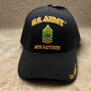 Puede incluir: Gorra de béisbol negra con texto bordado en dorado "U.S. ARMY" sobre una insignia verde y dorada, y "MSG RETIRED" debajo. La visera tiene "U.S. ARMY" bordado en dorado. Una gorra de temática militar.