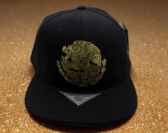 Gorra negra con visera plana de Águila Mexicana. Gorra con visera plana de Águila Mexicana bordada en oro. Gorra mexicana. Gorra con águila mexicana. Gorra negra de México. Gorra MX.