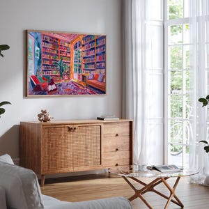 K&ouml;nnte beinhalten: Ein Gem&auml;lde, das das Innere einer farbenfrohen Bibliothek mit B&uuml;cherregalen voller B&uuml;cher, einem gro&szlig;en Fenster und zwei St&uuml;hlen zeigt. Das Gem&auml;lde ist gerahmt und h&auml;ngt an einer wei&szlig;en Wand.