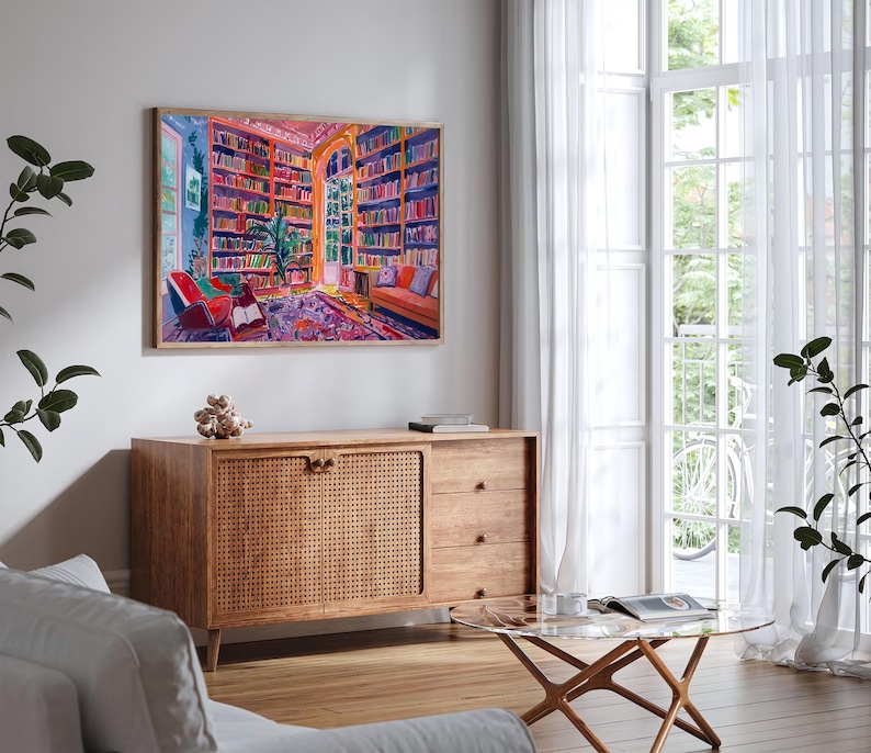 K&ouml;nnte beinhalten: Ein Gem&auml;lde, das das Innere einer farbenfrohen Bibliothek mit B&uuml;cherregalen voller B&uuml;cher, einem gro&szlig;en Fenster und zwei St&uuml;hlen zeigt. Das Gem&auml;lde ist gerahmt und h&auml;ngt an einer wei&szlig;en Wand.