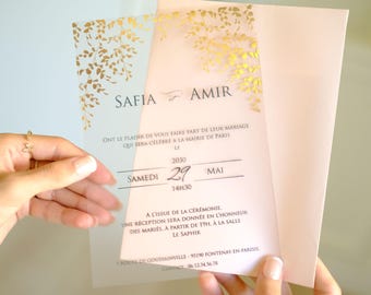 May include: A clear acrylic wedding invitation with gold foil floral accents. The invitation reads "Safia & Amir" and includes the date and time of the wedding ceremony. The invitation also includes the location of the reception, which is at "Le Saphir".