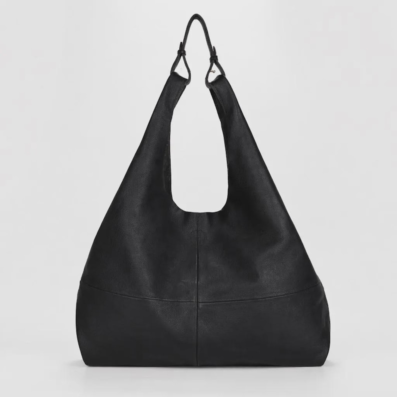Oversized black leather hobo bag with a soft slouchy silhouette and minimalist modern design. Elegant genuine leather shoulder tote featuring a spacious large capacity interior, smooth pebbled texture, adjustable shoulder straps, and chic quiet luxury aesthetic. Stylish women’s everyday handbag perfect for work, travel, shopping, and daily essentials. Trendy oversized leather tote purse, designer inspired carryall bag, casual minimalist fashion accessory, laptop friendly shoulder bag