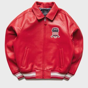 Side angle view of men’s red leather bomber jacket made from premium genuine sheepskin leather with smooth texture and durable stitching. This oversized streetwear leather jacket features classic ribbed cuffs, bomber waistband, and embroidered aviation patches that enhance the retro aviator style. Designed for comfort and fashion, this leather jacket pairs well with jeans, cargo pants, and sneakers.