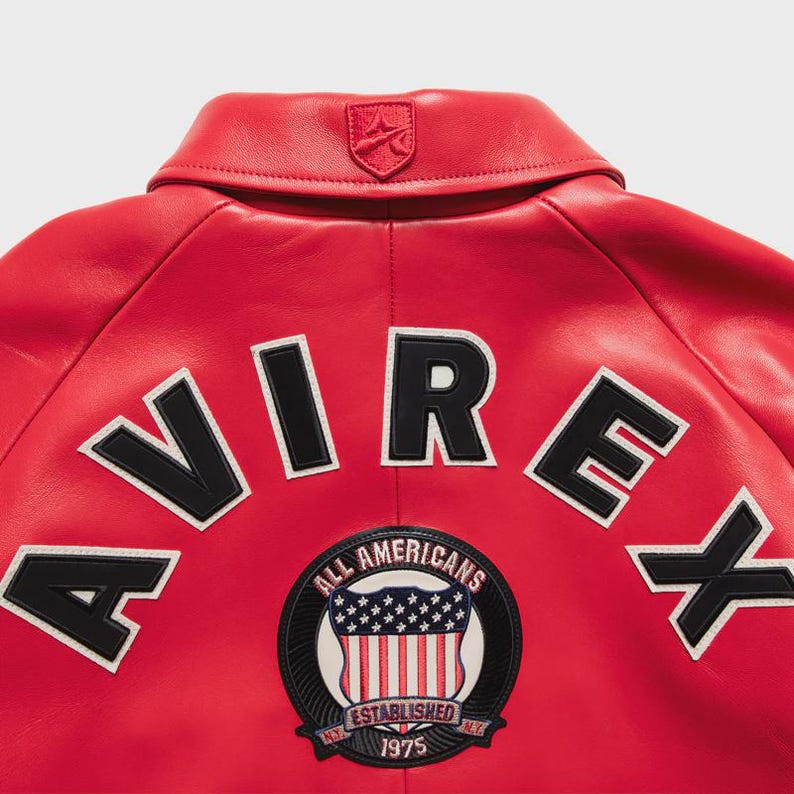 Men’s oversized red leather bomber jacket worn by model showcasing relaxed streetwear fit and urban fashion style. Crafted from genuine leather, the jacket features embroidered chest patches, ribbed cuffs, and durable zipper closure. Perfect for street fashion outfits, travel looks, and everyday casual wear.