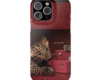 May include: A phone case featuring a leopard cub peering out from a red jewelry box. The case has a glossy finish and a camera lens cutout. The text "Collection les must" is visible.