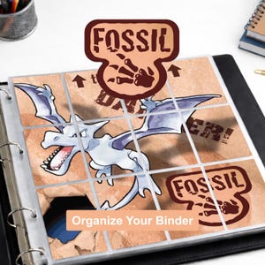 May include: A black three-ring binder containing a nine-pocket plastic page protector sheet. The sheet displays a tan background with a graphic of a white winged creature, the text FOSSIL, and the text Organize Your Binder in a peach box.
