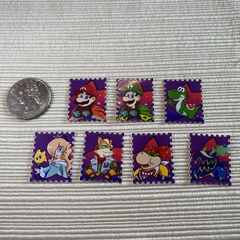Puede incluir: Una colecci&oacute;n de siete pegatinas rectangulares moradas con varios personajes de la franquicia de videojuegos Super Mario. Las pegatinas incluyen a Mario, Luigi, Yoshi, Rosalina, Fox, Bowser y un personaje con una m&aacute;scara azul. Se incluye una moneda como referencia de tama&ntilde;o.