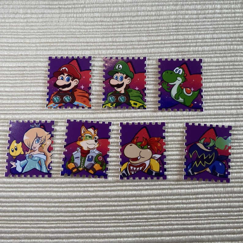 Puede incluir: Siete pegatinas rectangulares coloridas con personajes de la serie de videojuegos Super Mario. Las pegatinas tienen un borde morado y representan a Mario, Luigi, Yoshi, Rosalina, Fox, Bowser y un Shy Guy.