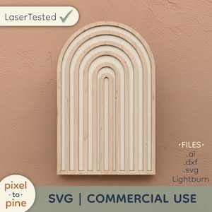 May include: A light-coloured wooden wall art piece with an arched design. The art features a series of concentric arches and vertical lines, creating a layered effect. The text "Laser Tested" and "pixel to pine" are visible. The bottom of the image reads "SVG | COMMERCIAL USE".