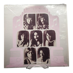 May include: A vintage vinyl record album featuring a pink and gray design with the text "Midnight Radio" and images of seven people. The album is in a clear plastic sleeve.