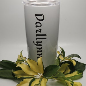 以下が含まれることがあります： 黒い文字で「Darlynn」と書かれた白いステンレス製のタンブラーです。