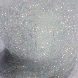 以下が含まれることがあります： 虹色の白いクラフトファイバーのクローズアップ。スパークルヤーンとしても知られています。繊細な輝きがあります。繊維は柔らかくふわふわで、クラフトに輝きを加えるのに最適です。