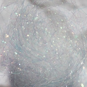 以下が含まれることがあります： 白くてふわふわした虹色の素材のクローズアップ。キラキラした質感です。この素材は、クラフトや装飾に使用される可能性があります。