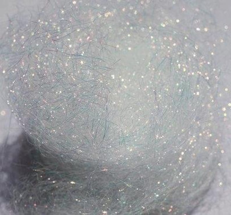 以下が含まれることがあります： 虹色の白いクラフトファイバーのクローズアップ。スパークルヤーンとしても知られています。繊細な輝きがあります。繊維は柔らかくふわふわで、クラフトに輝きを加えるのに最適です。