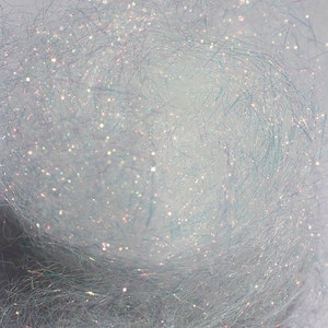 以下が含まれることがあります： 虹色の白いキラキラ糸のクローズアップ。糸は細かい繊維でできており、繊細でキラキラした外観をしています。