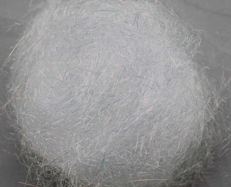 以下が含まれることがあります： 虹色の青と緑の繊維のボールのクローズアップ。繊維は非常に細かく、柔らかくふわふわした質感です。