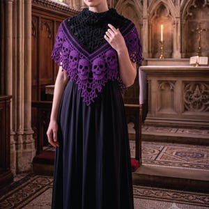 Puede incluir: Un chal de ganchillo en negro y morado con un patrón repetido de calaveras a lo largo del borde inferior y una sección superior negra texturizada, sobre un vestido negro sencillo hasta el suelo. El chal tiene forma triangular con encaje.