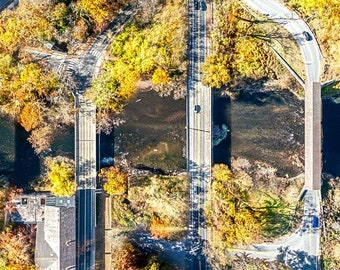 Può includere: Vista aerea di una strada con diversi ponti che attraversano un fiume. Gli alberi che costeggiano il fiume sono un mix di verde e giallo, a indicare il cambio di stagione.