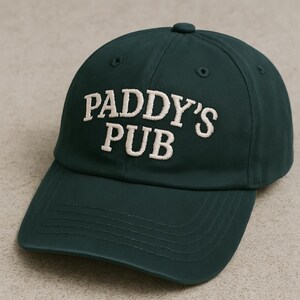 May include: A dark green baseball cap with the text "PADDY'S PUB" embroidered in white.