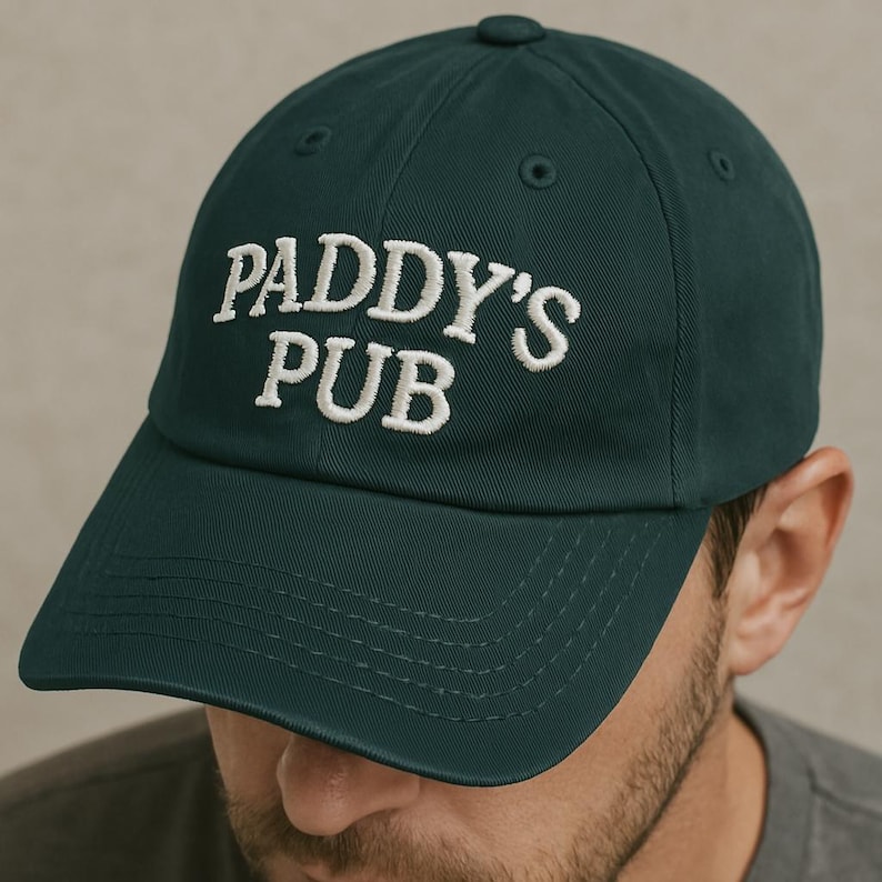 May include: A dark green baseball cap with white embroidered text that reads "Paddy's Pub".