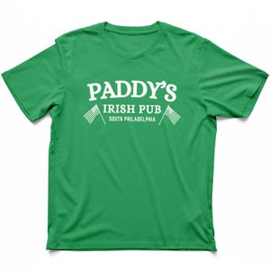 Puede incluir: Camiseta verde con texto blanco que dice "Paddy's Irish Pub South Philadelphia" con dos peque&ntilde;as banderas americanas a cada lado del texto.