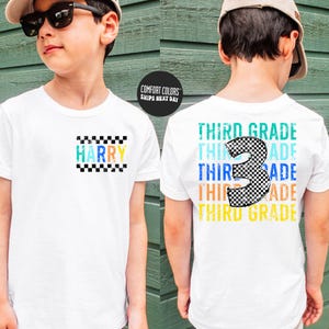 May include: White t-shirt with "HARRY" in colorful letters and a checkered design. The back of the shirt features "THIRD GRADE" in various colors with a checkered number 3. A Comfort Colors shirt.