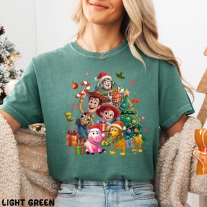 A woman wearing a green t-shirt with a Christmas-themed graphic featuring characters from the Toy Story movie.